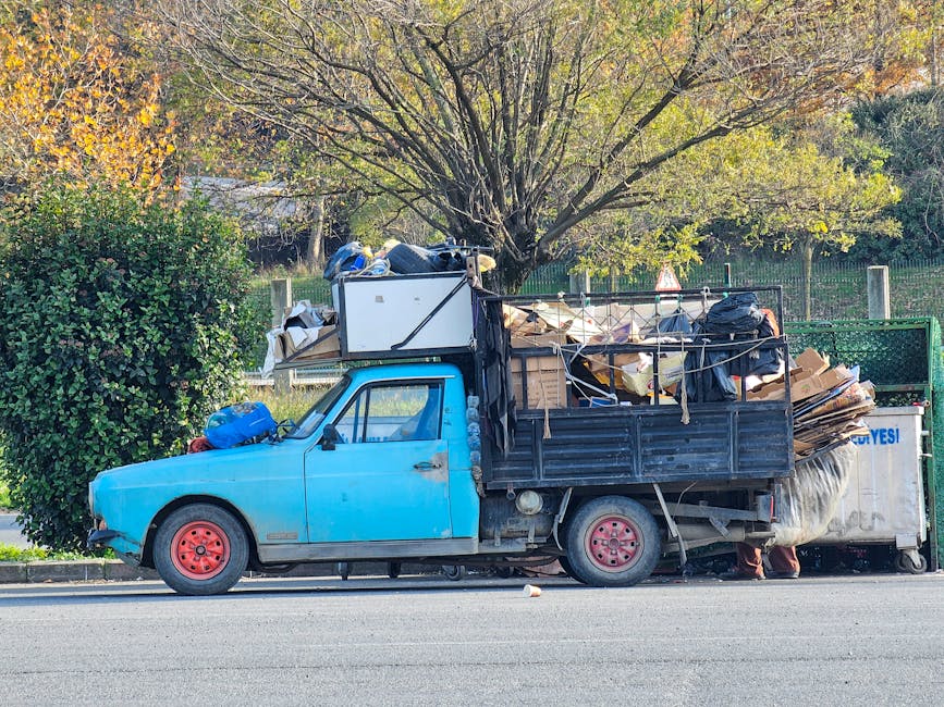 The image shows the rear portion of a white commercial van parked on a paved street outside a building with a glass window and a white wall feature. Three large blue rubbish bags, made of plastic with